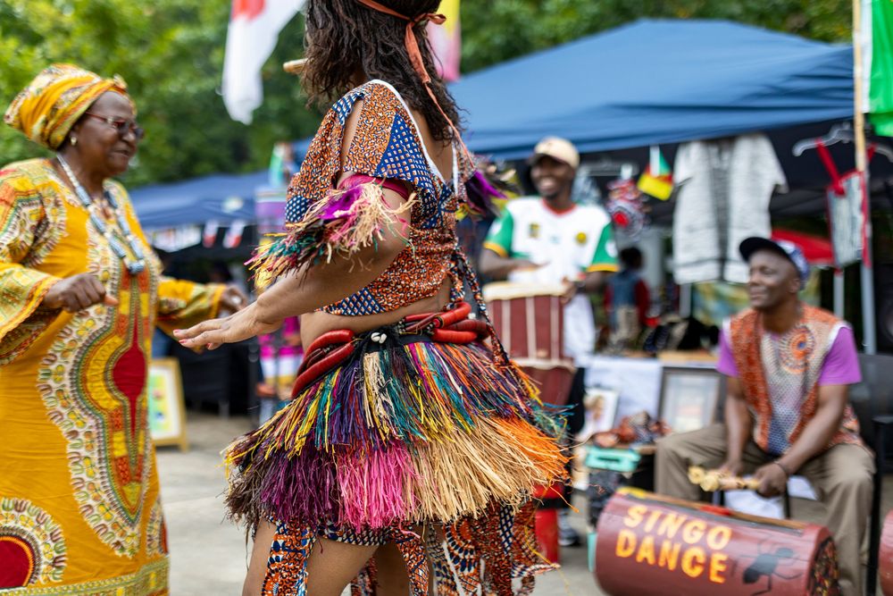 Colorful festival performers in vibrant traditional costumes dancing and celebrating at an outdoor cultural event.