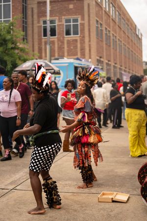 Dancers in colorful traditional costumes perform at an outdoor cultural festival on a city street.