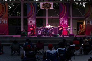 Concert venue exterior at night with pink neon lighting.