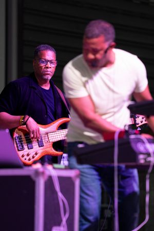 Bass guitarist performs on stage with purple lighting effects.