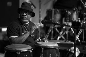 Drummer performs on stage in dramatic black and white lighting.