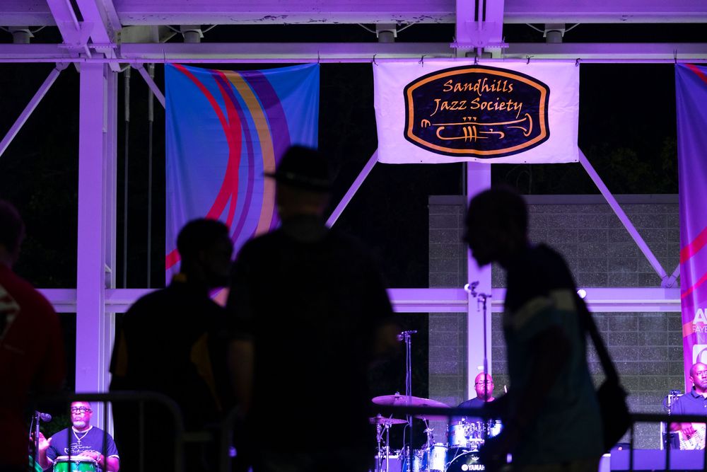Wedding reception dance floor illuminated with purple uplighting and dark silhouettes of guests dancing.