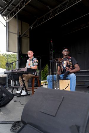 Musicians and performers setting up equipment on a dark stage at an outdoor venue.