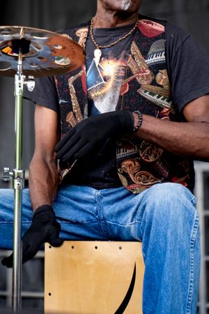 Musician in black t-shirt and jeans performing on stage with percussion instruments.