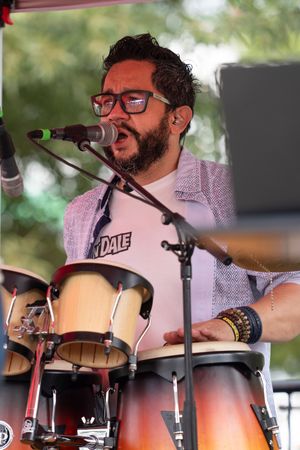 Drummer performing on stage with multiple percussion instruments and microphones.