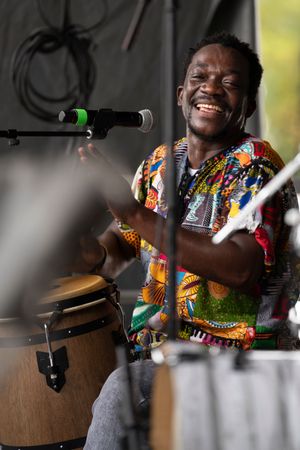 Drummer in colorful African print outfit performing enthusiastically on stage.