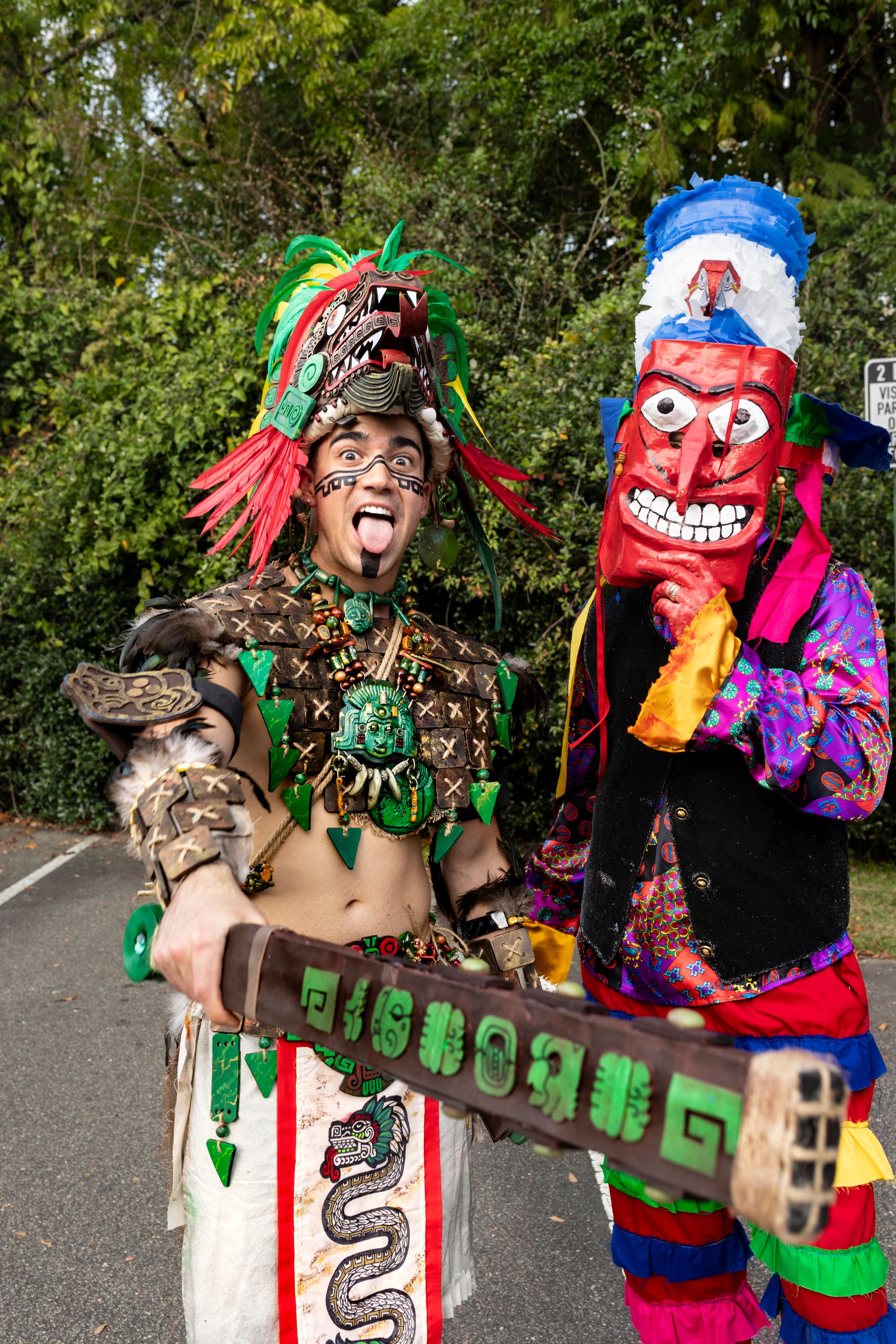 Performers in colorful costumes and masks dance and pose together in a playful sequence.