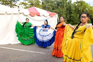 Dancers in colorful traditional Mexican dresses perform at an outdoor cultural festival.