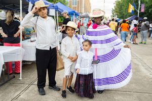 Festival attendees in traditional cultural dress with purple and white skirts.