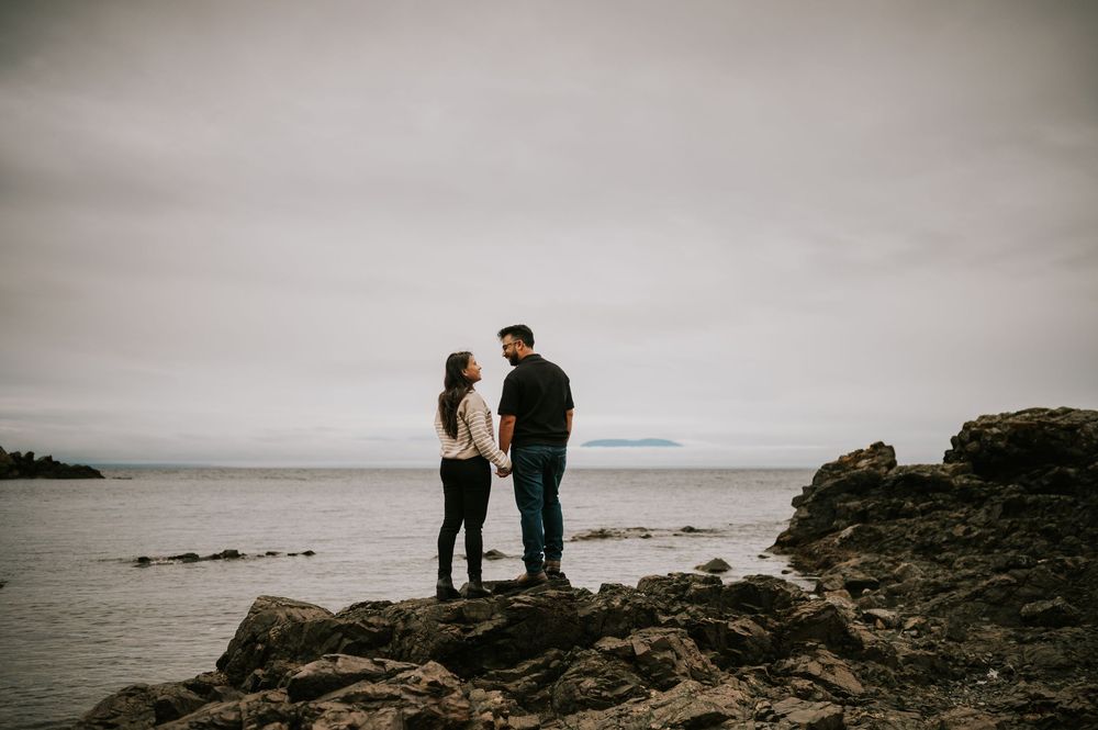 Professional Photographer Engagement Photoshoot at Neck Point Park, Nanaimo, Vancouver Island of couple standing on rocky beach by ocean