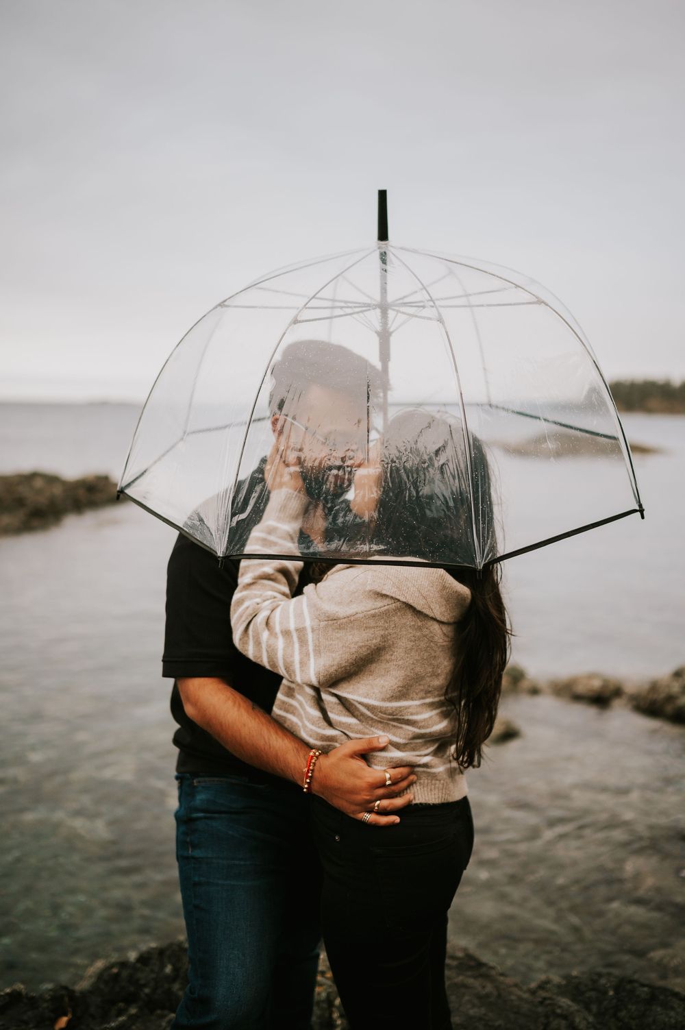 Professional Photographer Engagement Fall Photoshoot at Neck Point Park, Nanaimo, Vancouver Island of couple on rocks in rain with umbrellas