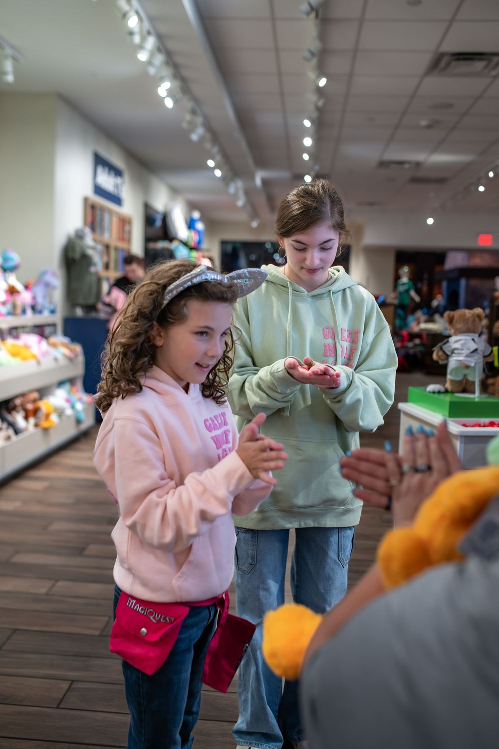 Children interacting with toys in a brightly lit retail store with wood floors and display shelves.