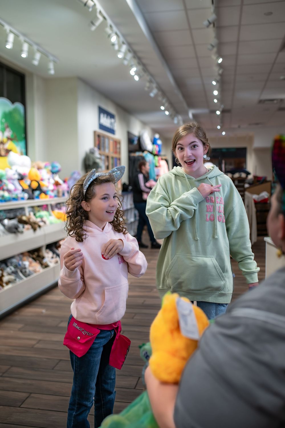 Two people show excitement while shopping in a store filled with plush toys and bright lighting.