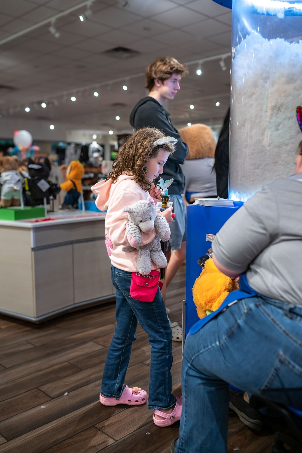 Young visitor in a pink sweater and jeans explores an interactive exhibit at a modern science museum.