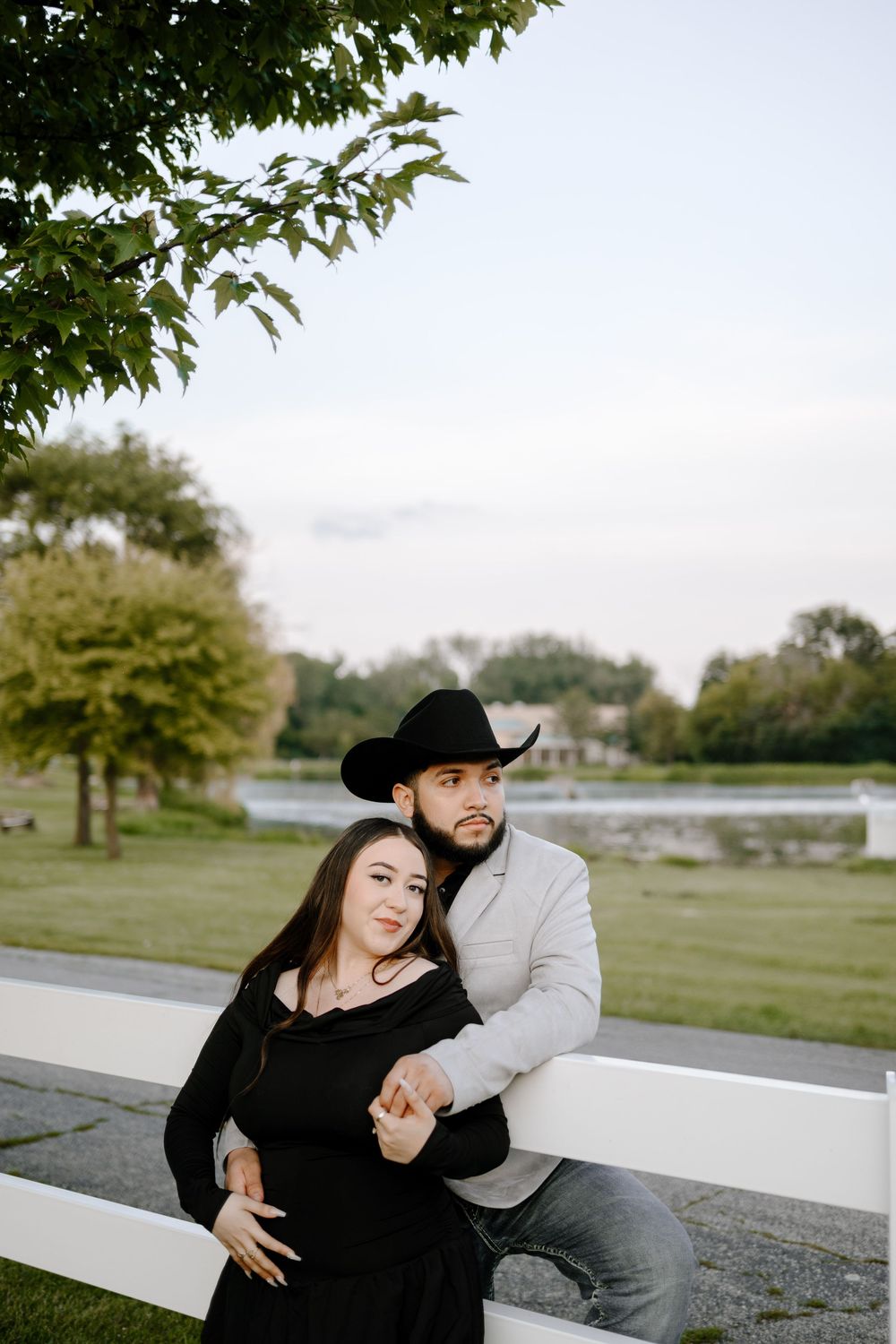 A couple sits together on concrete steps outdoors, sharing intimate moments in a park-like setting.