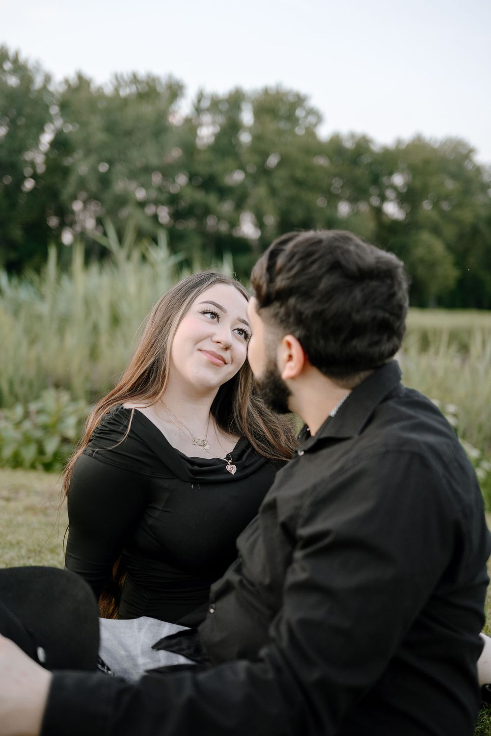 A couple shares intimate moments together in a field of tall grass during an outdoor photoshoot.