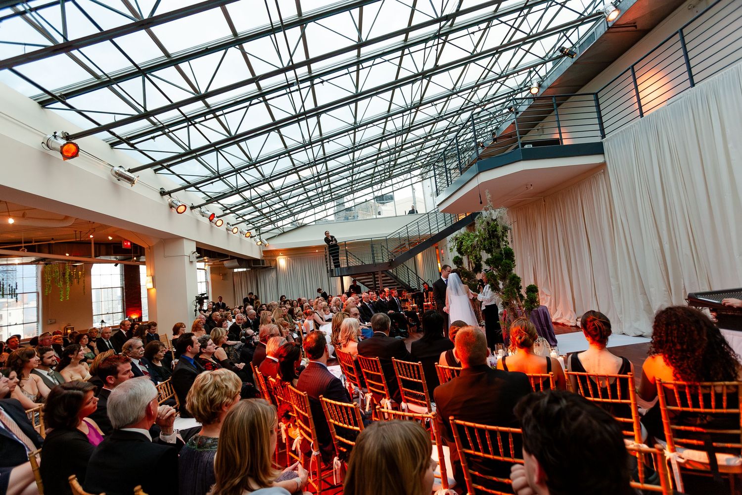 A panoramic view of a crowded corporate event space with glass ceiling and modern interior design.