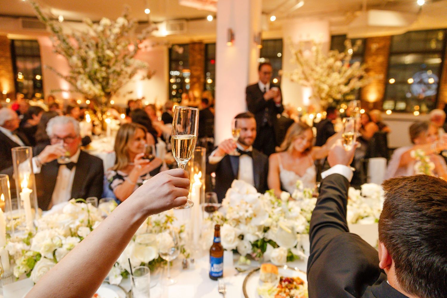 Elegant wedding reception dinner with floral centerpieces and warm ambient lighting.