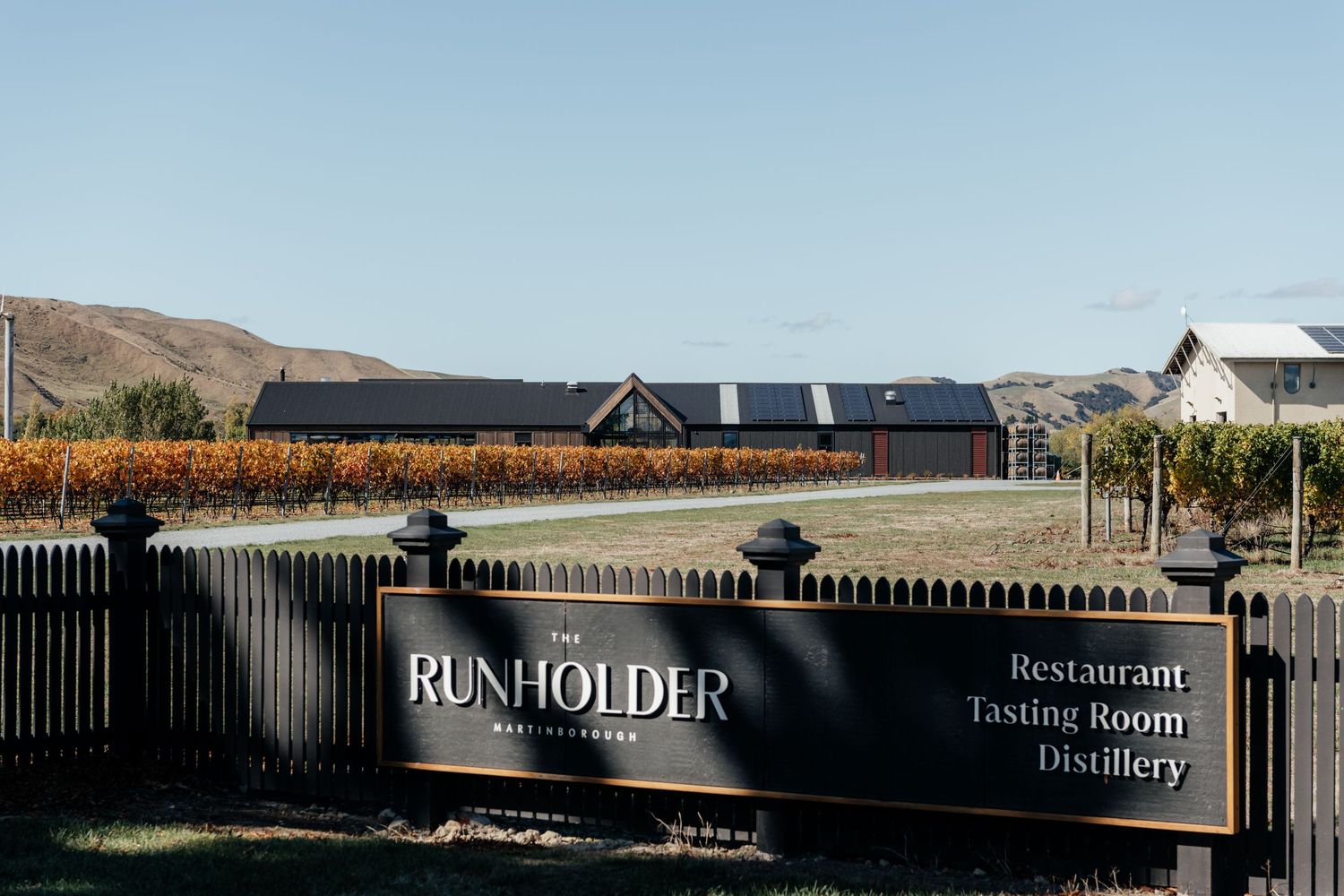 Exterior view of Runholder restaurant and distillery building with mountains visible in background by August and Vine