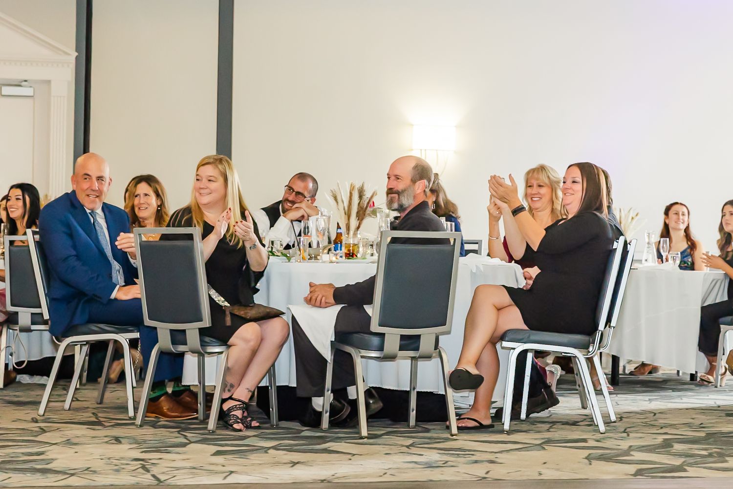 Wedding guests seated at elegant white tables during a reception in a modern venue.