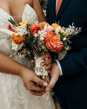 Close-up details of wedding bouquet featuring orange and coral roses with white floral accents.