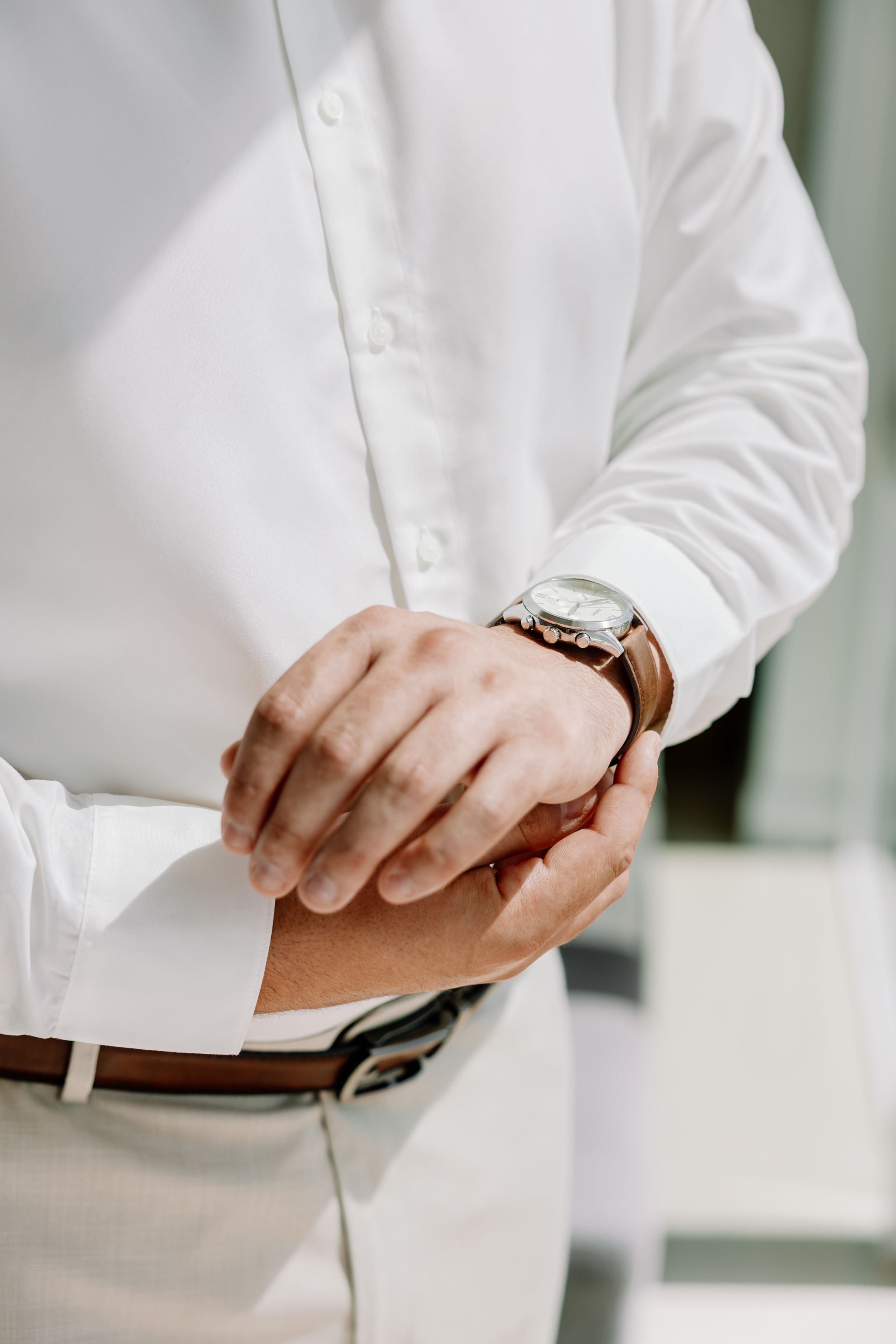 Close-up shots of hands buttoning up a crisp white dress shirt.