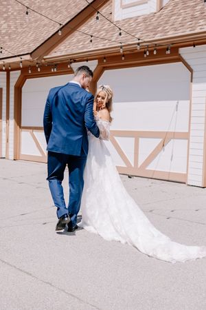 Wedding couple dancing under string lights at a rustic outdoor venue.