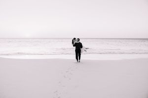 Minimalist black and white beach photography showing silhouettes walking along the shoreline.
