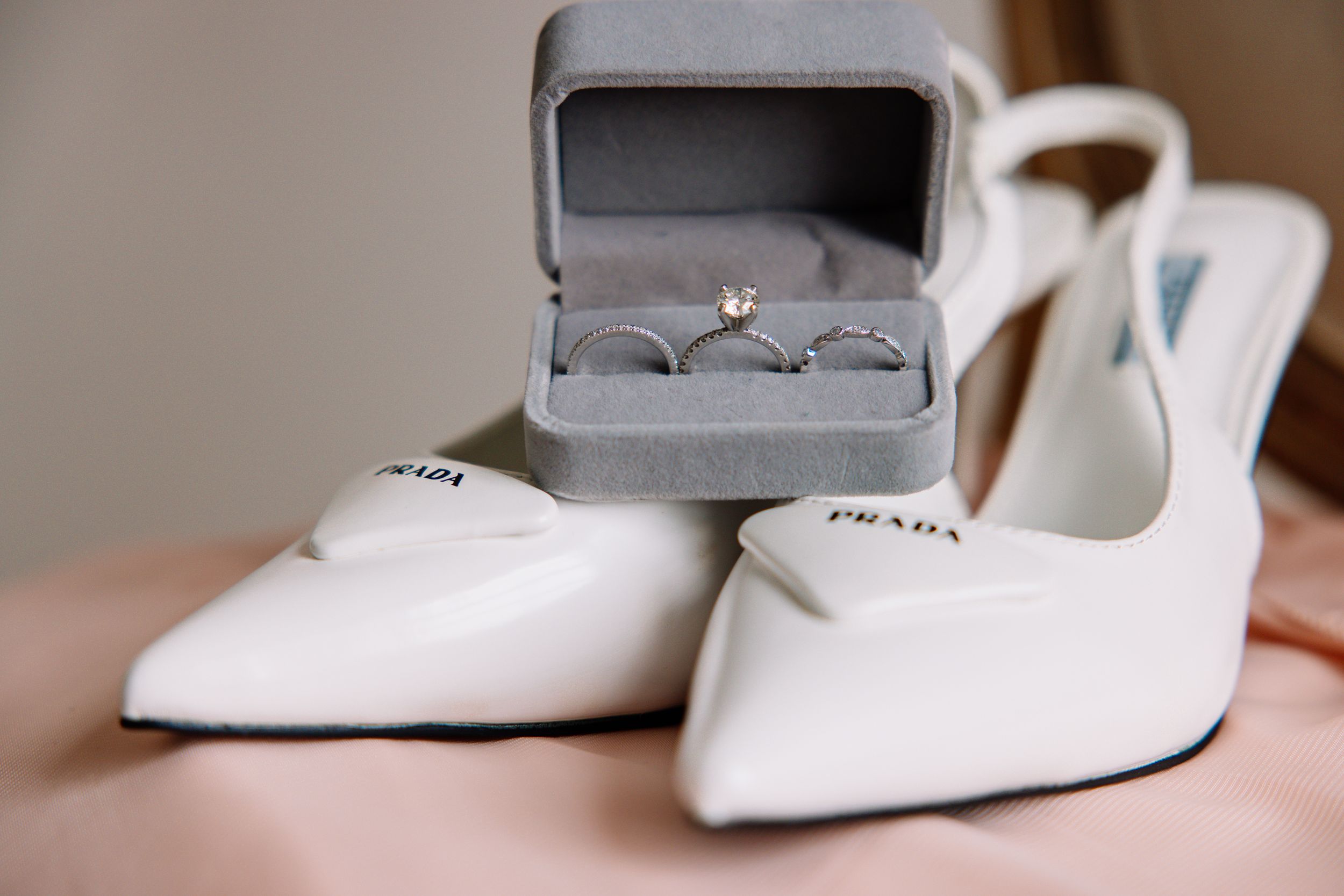White bridal shoes displayed in gray jewelry boxes with soft focus.
