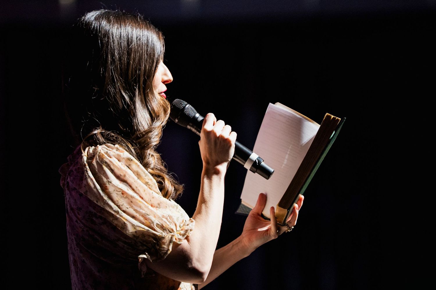Woman reading out of a book into a microphone