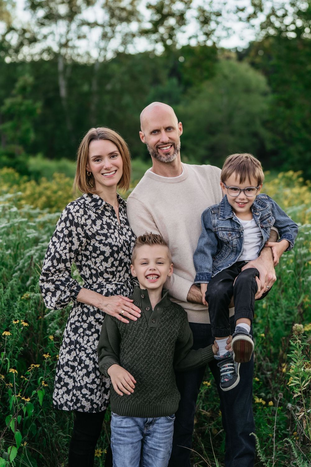A family wearing casual clothes poses together in a field of wildflowers during a Cascade Valley Metro Park Family session in Akron, Ohio