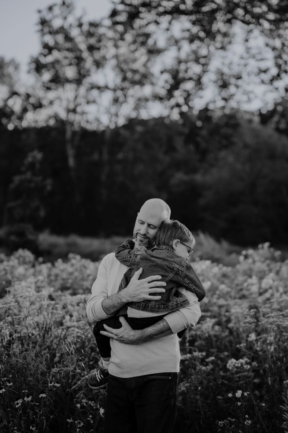 Black and white photos show tender moments of embracing in a garden setting with flowers and trees at family photo session in Akron, Ohio
