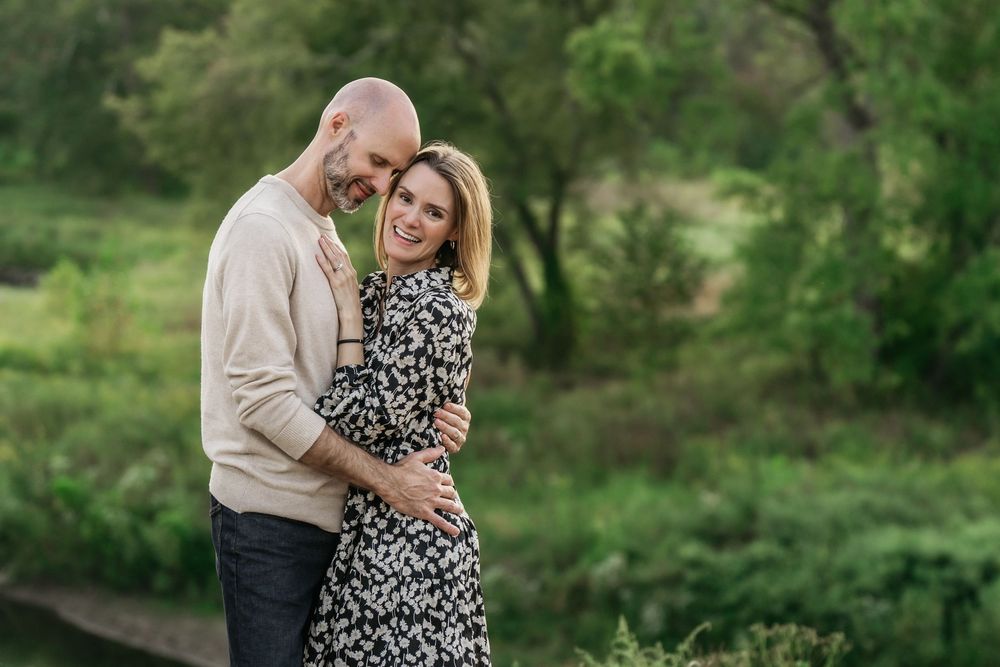 A couple shares a romantic moment together outdoors in a lush green garden setting during a summer photo session in Akron, Ohio
