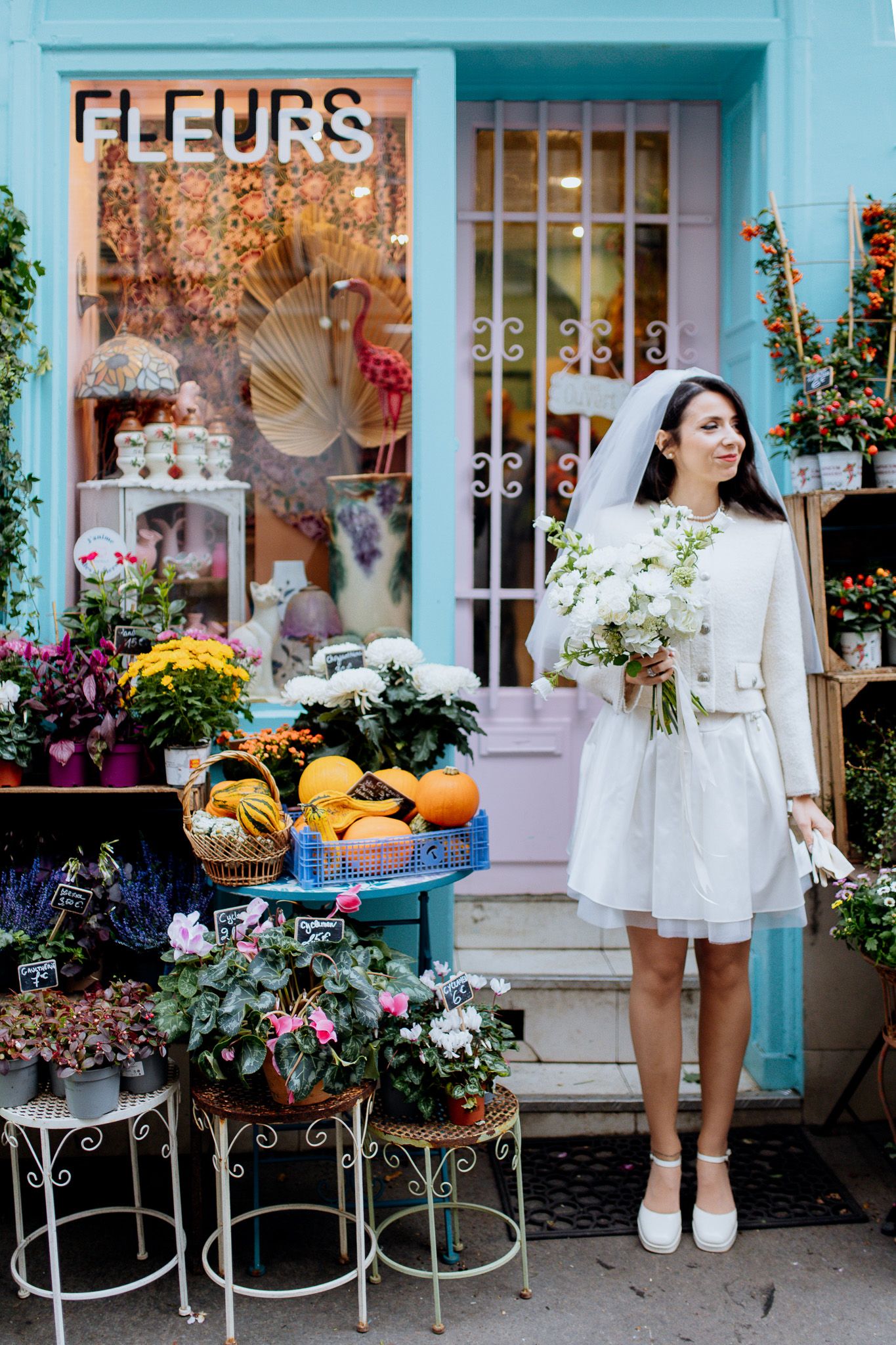 mariée qui pose avec son bouquet devant le fleuriste