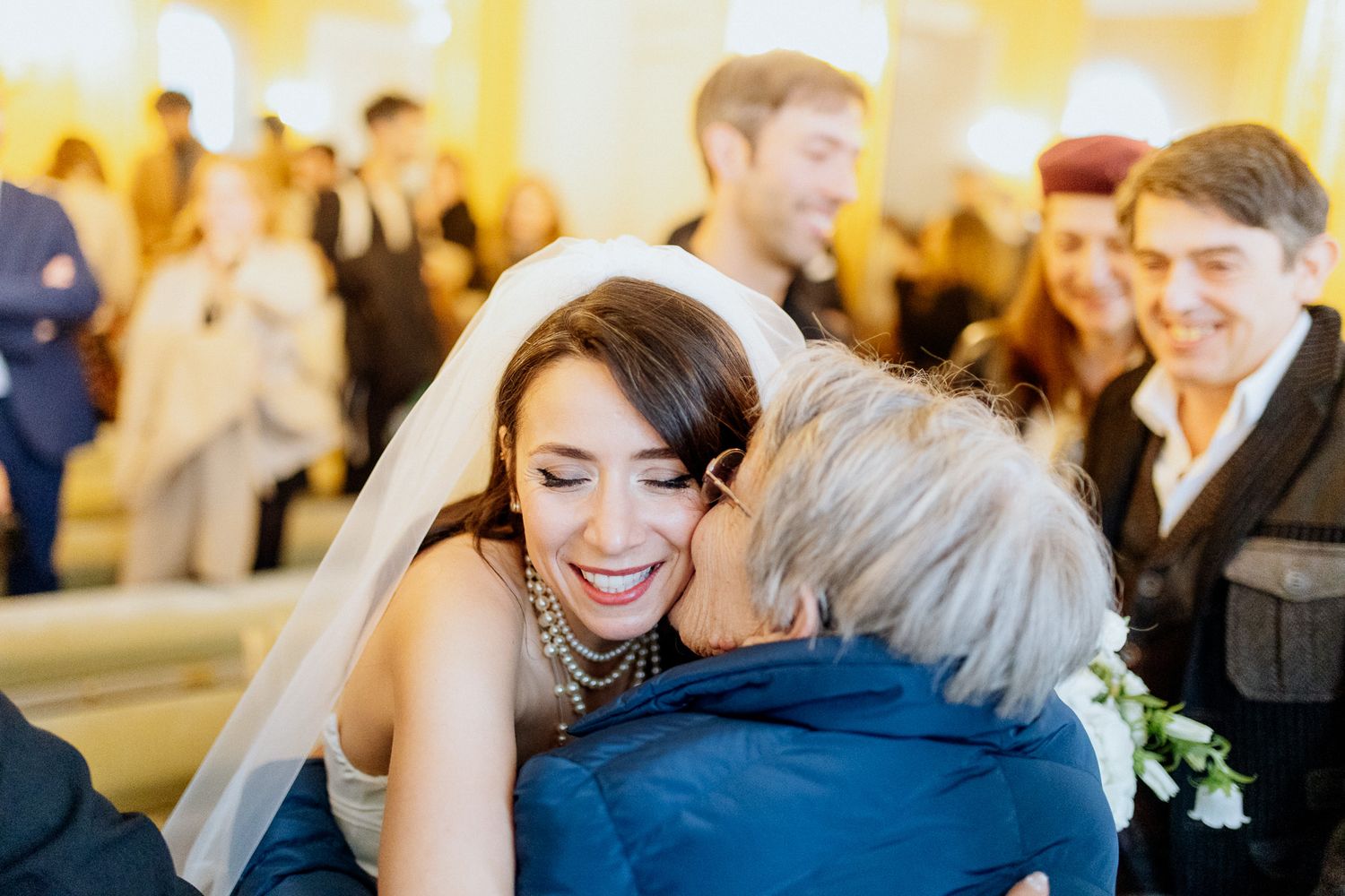 mariée qui sourit pendant que sa grand-mère l'embrasse