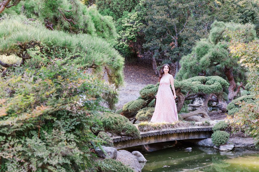 A serene Japanese garden path winds through lush greenery with stone lanterns and bridges.