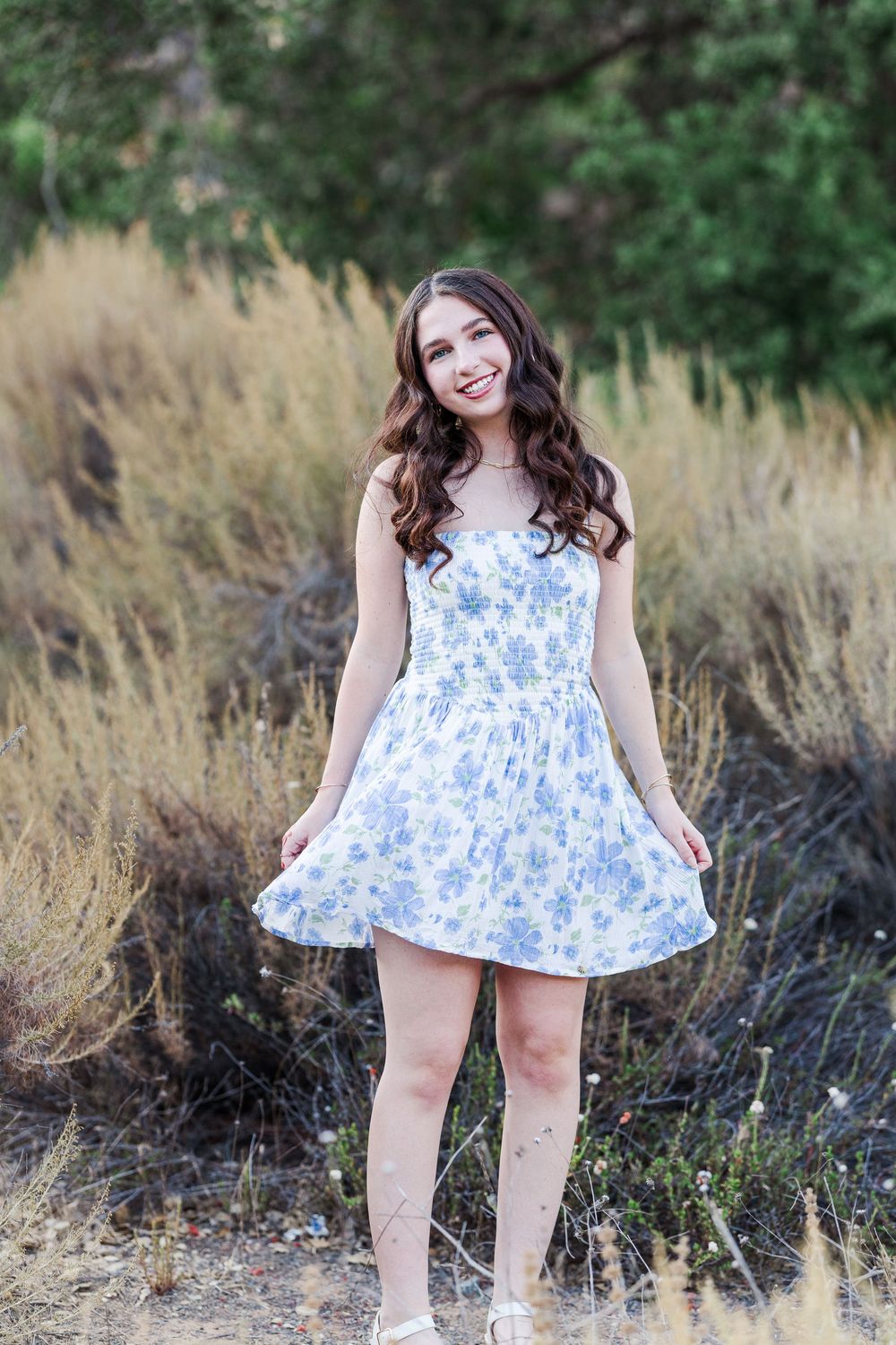A sequence of photos showing a floral blue and white summer dress in a golden field at sunset.