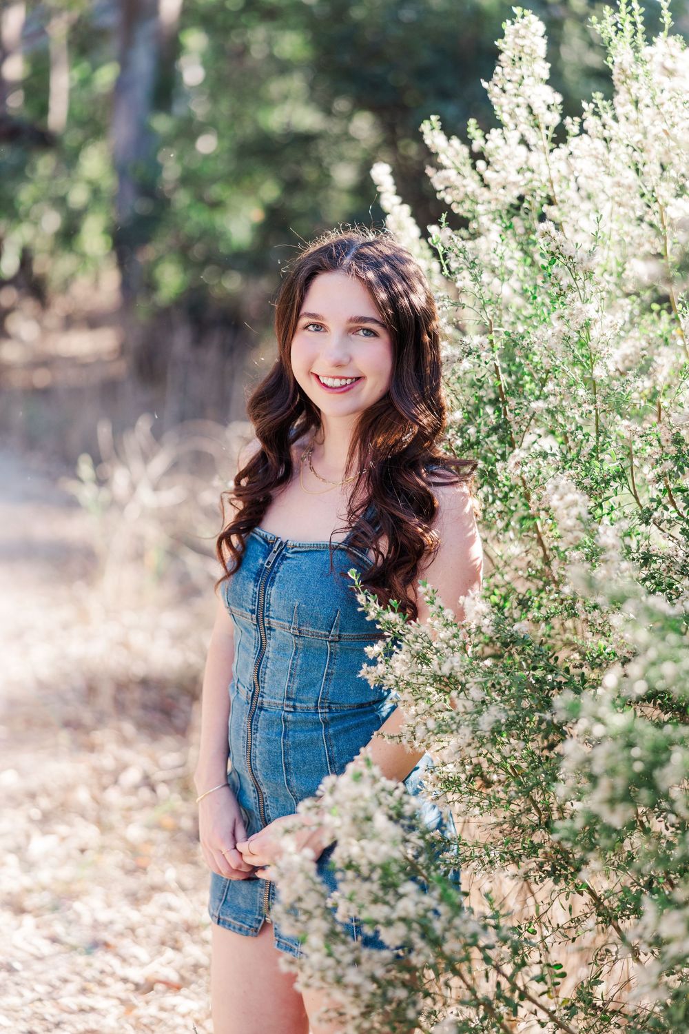 Outdoor photoshoot with white wildflowers and denim outfit in natural sunlight.