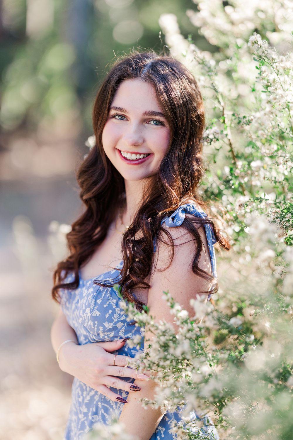 Lifestyle portrait with flowing floral dress among blooming white flowers in garden setting.