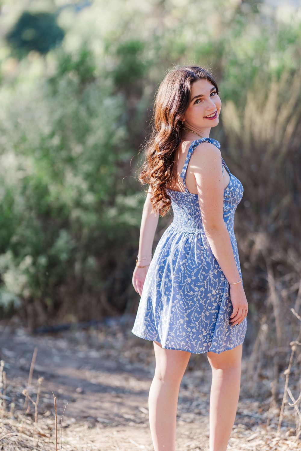 Summer fashion shoot featuring blue floral dress in natural outdoor lighting.