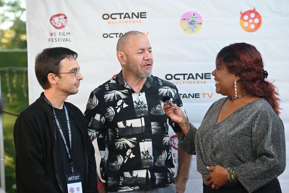 A group of people having an animated discussion at a professional event with an Octane logo visible in the background.