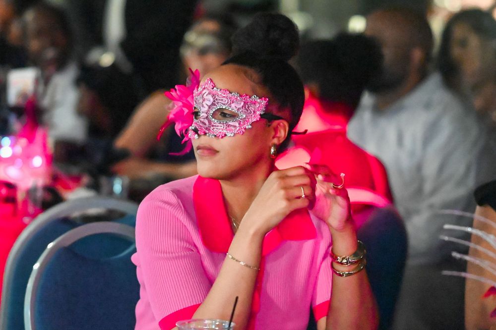 People in formal attire enjoying an evening event with pink lighting.