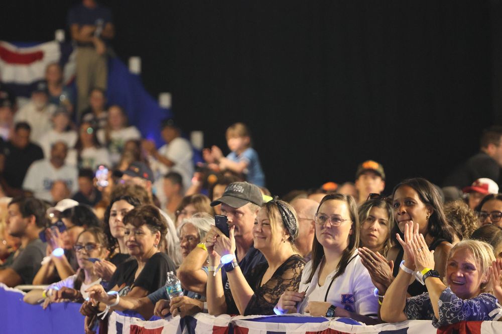 Crowd of excited spectators cheering and waving their hands in the air at a sporting event.