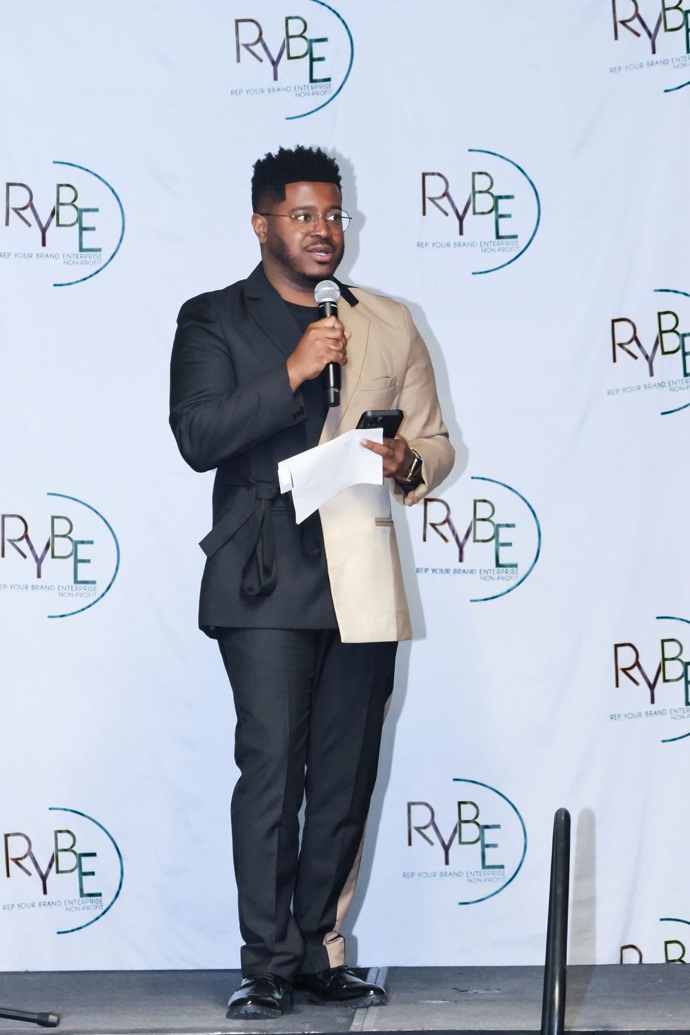 Speaker presenting on stage with branded backdrop at corporate event.
