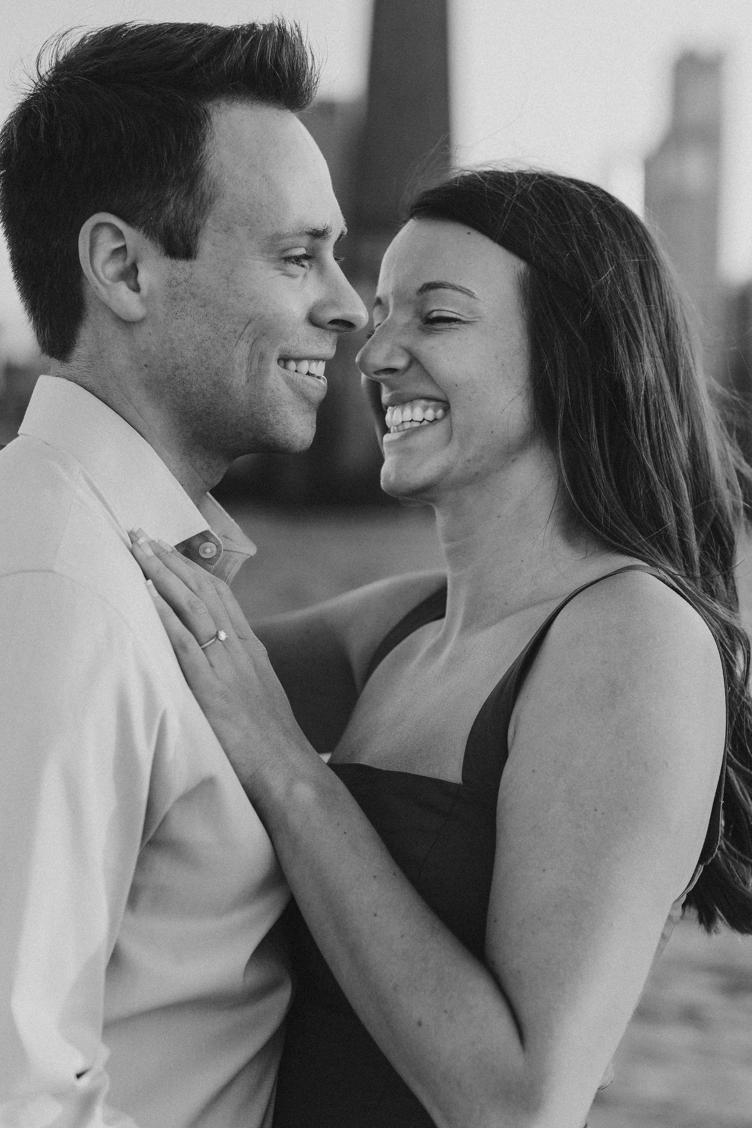 Black and white photo series of a couple laughing and embracing by the waterfront.