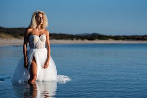 Ethereal wedding photography session with a white dress floating in tranquil blue waters.