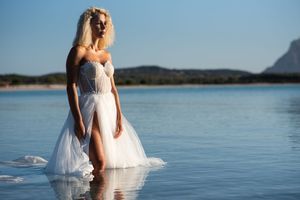 Artistic bridal portrait showing a flowing dress against serene coastal waters.