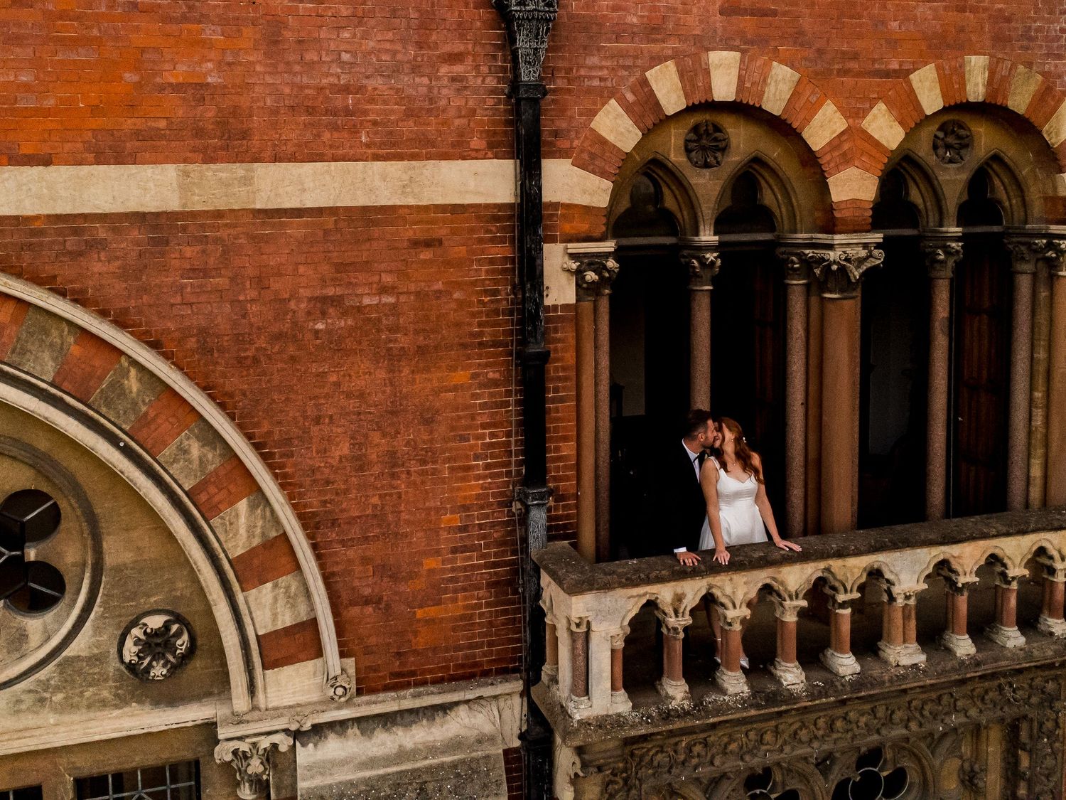 Couple poses in ornate brick archways during their wedding photoshoot.