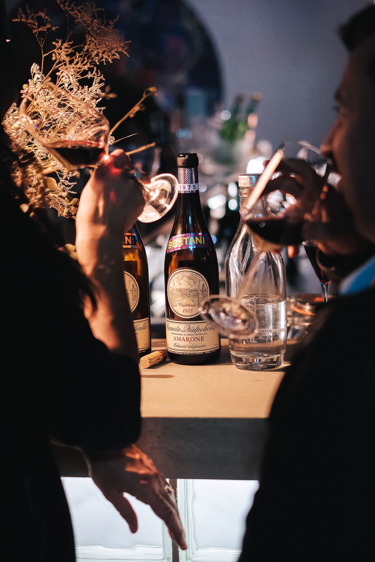 Artfully lit bar setup with decorative branches and bottles in moody lighting.