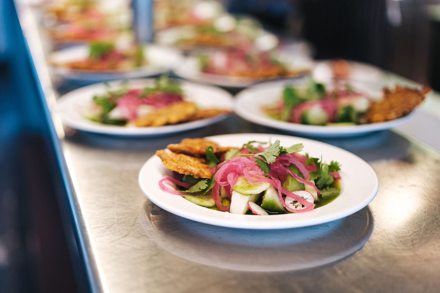 Elegantly plated dishes arranged on white plates in restaurant lighting.